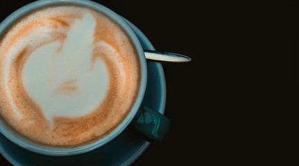 Latte beautiful arts coffe. Blue cup of hot coffee on black surface.