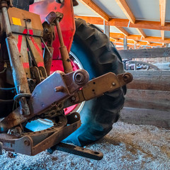 Square Back view of an old vintage tractor with black wheels and red paint at a barn
