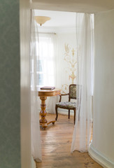 View to beautiful romantic old vintage room with rustic furniture, sunny light from window. Classicism interior.