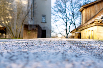 Snow on the road with old buildings in a town. Winter, sunny day. Close up, selective focus, copy space.