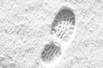 Track from a boot on white snow. Black and white photo.