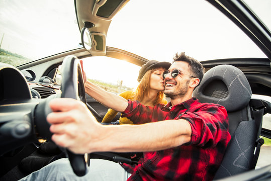 Happy Couple Driving A Convertible Car At Sunset On The Road