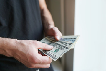 Bundle of dollars in male hands. Currency in hundred-dollar bills. paper money. Recalculation of cash.