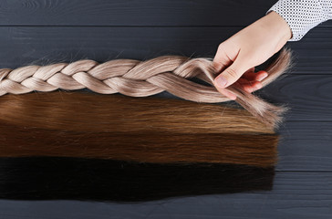 The male hand holds sections of hair for extension. © Bidzilya