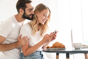 Happy beautiful young couple having breakfast at the kitchen