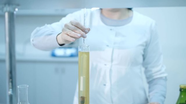 Lab technician with an alcoholmeter measures the degree of alcohol in a beer drink