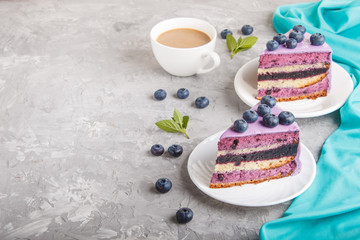Homemade cake with souffle cream and blueberry jam with cup of coffee on a gray concrete  background. side view.