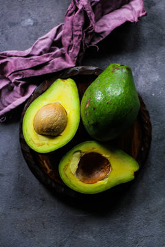 Photo of ripe organic avocado on dark background. Wooden table. Nutritious Fruit. Healthy food concept. Tropical fruit. Top view. Green. Image
