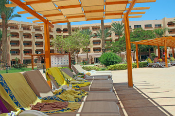 Empty deck chairs with towels on tropical resort. Chaise longues near hotel