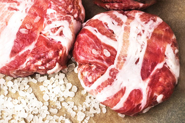 Meat raw round cutlets wrapped in bacon and coarse salt. Ingredients for making a hamburger. A large amount of salt in the product. The view from the top. The concept of meat lovers