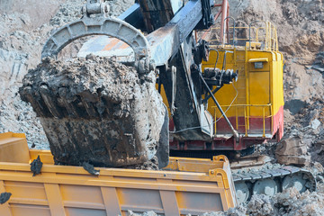 the process of loading soil into a dump truck with a large excavator for delivery to the construction site