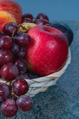 Fototapeta na wymiar red grape berries and fresh fruits in a straw basket on a dark wooden background.