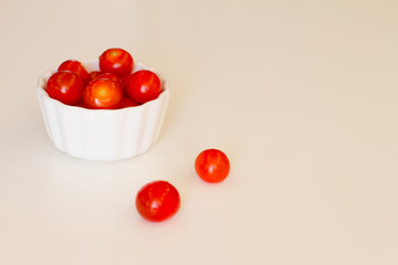 lots of cherry tomatoes in a white plate on a white background. texture. concept of fresh vegetables and healthy food. space for text. top view of tomatoes. ripe harvest.