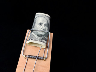 Dollars in a mousetrap on a black background. Wooden trap with bait and mechanism for rats and...