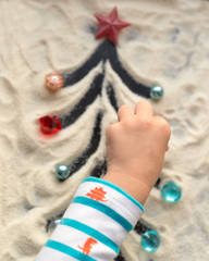 Creative arts. Children's creativity. Child draws a Christmas tree on the sand. Сhildren's creative work.