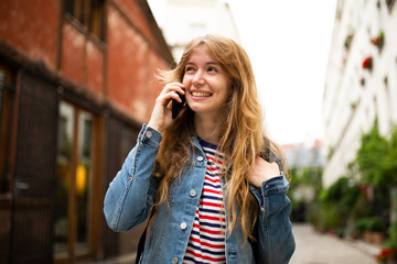 smiling young woman talking with mobile phone outside in city