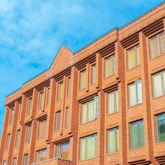 Fototapeta na wymiar Square frame Exterior of a multi storey building with red brick walls and tall glass windows