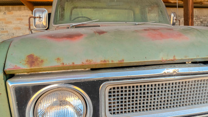 Pano Front view of the dirty and rusty exterior of an old vintage green car