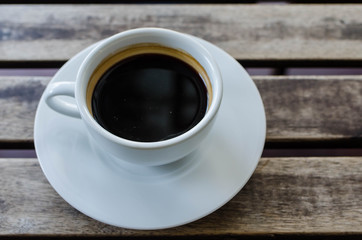 A cup of coffee with pattern in a white cup on wooden background