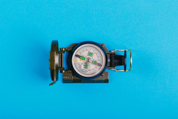 metal navigation travel compass on a blue background. search for a way. point of view
