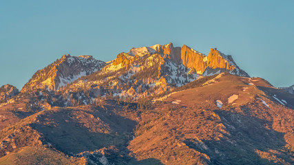 Obraz premium Pano frame Striking mountain peak with rugged slopes against blue sky on a sunny day