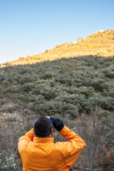 Hiker observes hills with binoculars