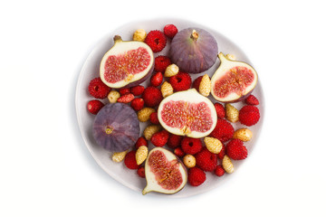 Fresh figs, strawberries and raspberries on white ceramic plate isolated on white background. top view