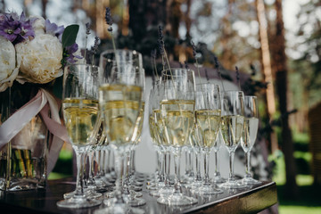 Glasses of with champagne decorated with lavender. Wedding in park. Outdoor decoration