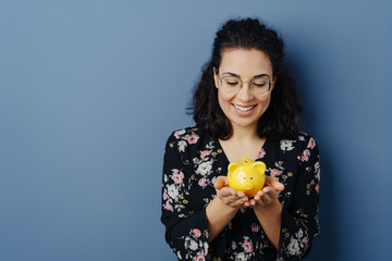 Successful young woman holding a yellow piggy bank