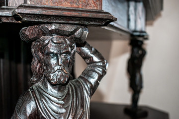 old wood carving. old man who has a heavy weight on his head. Macro shoot closeup. beautiful architecture.
