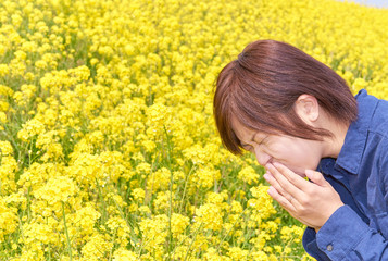 Fototapeta premium 菜の花畑でくしゃみをする若い女性