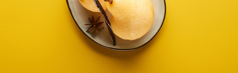 top view of delicious pear in wine with anise on plate on yellow background, panoramic shot