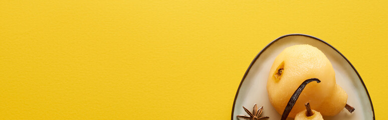 top view of delicious pear in wine with anise on plate on yellow background, panoramic shot