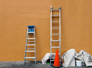 Exterior building wall with paint ladders and tarps. Nobody.
