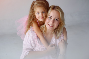 Beautiful woman with child. Woman in a pink pajama. Child in a bedroom in a pink dress.