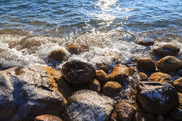 Stones on the sea beach. Pasture winter day. Clear water and sand. Kyrgyzstan, Issyk-Kul Lake