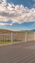 Vertical Back porch of a home with view of lake and mountain under cloudy blue sky