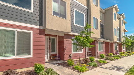 Pano Townhomes exterior with red gray and beige wall against blue sky on a sunny day