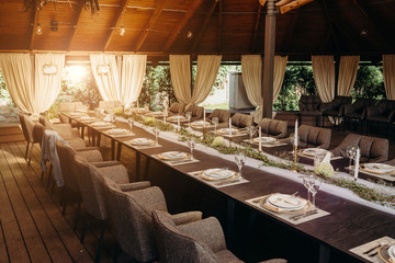 Outdoor wedding and romantic table setting in rustic style on wooden table. Plates, glasses, vintage silverware, blank rough tag and lavender flowers.