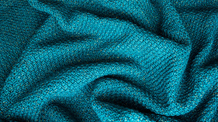 Fototapeta na wymiar Knitted green fabric with lurex. Randomly folded.