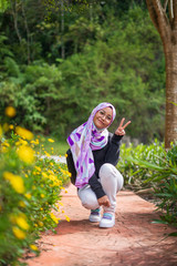 Beautiful attractive young Asian woman in hijab at flowers park, Cameron Highlands, enjoying beautiful nature view. Travel photo