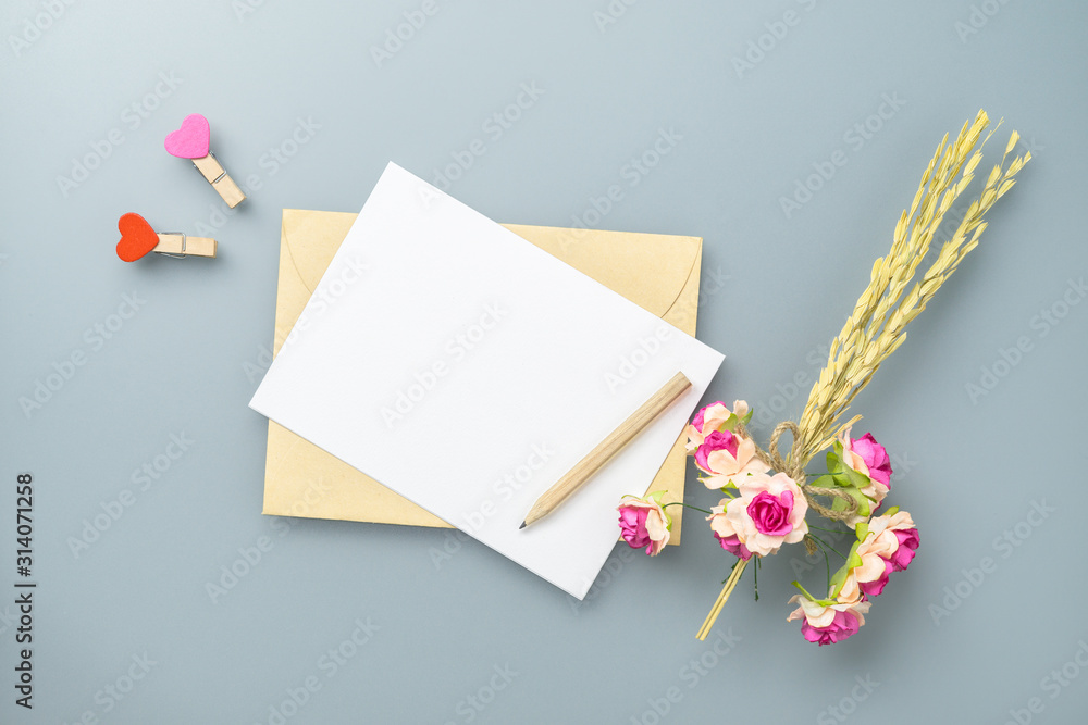 Aufkleber mockup blank postcard and envelope on grey table background with craft rose flower. mock up for eleg