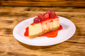 White plate with cheesecake New York and raspberries on wooden table