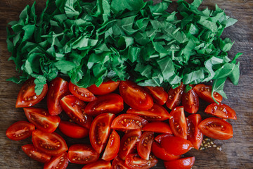Chopped tomatoes and bright green spinach on wooden rustic table. Top view. Copy, empty space for text
