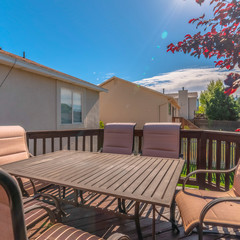 Square Table and chairs on the balcony of a home with stairs going down to the yard