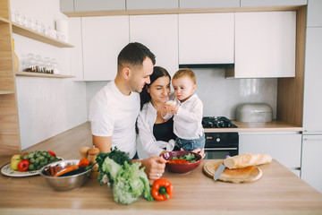 Family in a kitchen. Beautiful mother with little son. Father in a white t-shirt.
