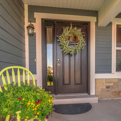 Square frame Porch and facade of home decorated with colorful flowers and wreath on the door