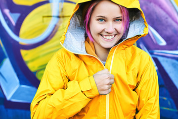 Urban bright portrait cool young woman in hood with cheerful smile wearing in yellow jacket posing...