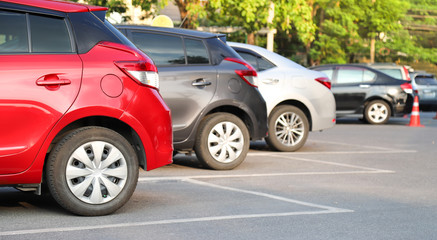 Closeup of rear, back side of red car with  other cars parking in outdoor parking area in bright sunny day. 