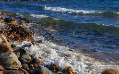 Stones on the sea beach. Pasture winter day. Clear water and sand. Kyrgyzstan, Issyk-Kul Lake